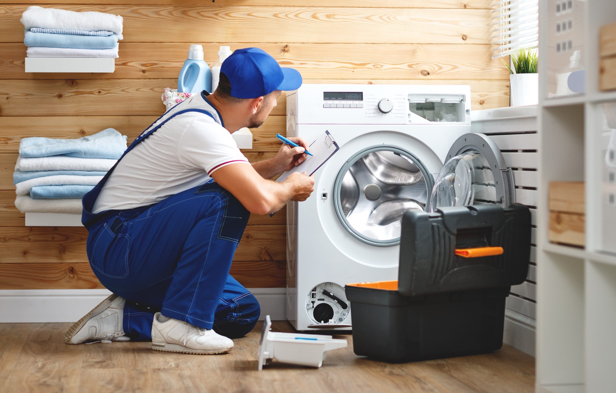 Technician inspecting a front-load washing machine with a toolbox